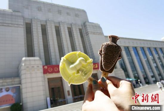2021年7月30日，游客手拿“銅奔馬”“彩陶瓶”造型的雪糕，在甘肅省博物館前拍照打卡?！「哒?攝