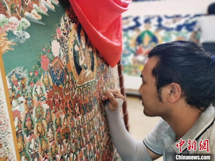 圖為更登才讓的徒弟繪畫唐卡?！?zhí)砀?攝