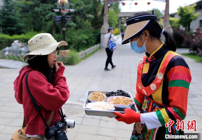 圖為身穿土族服飾的女性介紹當(dāng)?shù)靥厣〕??！⊙Φ?攝