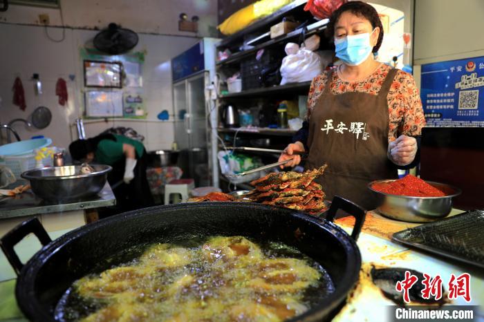 圖為平安驛·河湟民俗文化體驗(yàn)地內(nèi)的商戶炸干板魚?！⊙Φ?攝