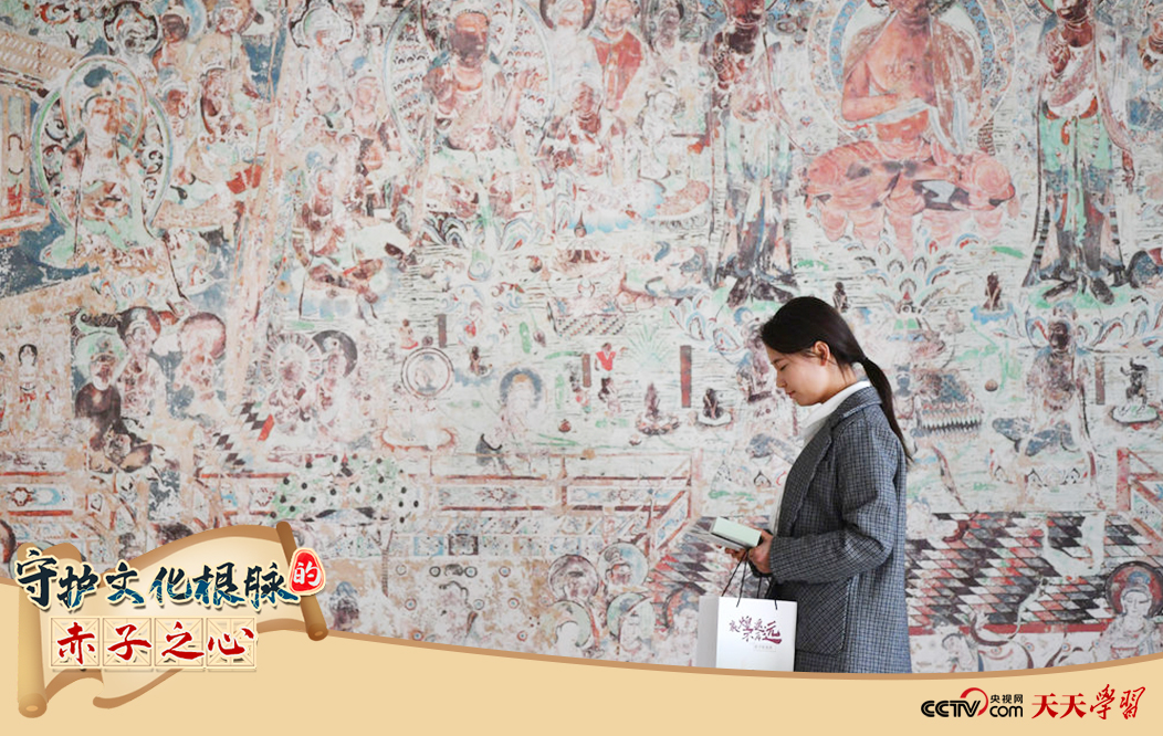 2023年4月25日，敦煌研究院文物數(shù)字化保護團隊創(chuàng)意營銷人員廖雪婷從一幅高保真復(fù)制壁畫前走過。