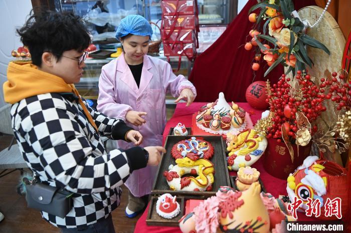 1月25日，隨著春節(jié)臨近，蘭州一花饃店“龍”元素花饃熱銷(xiāo)。圖為工作人員向顧客推薦“龍”元素花饃。九美旦增 攝</p><p>