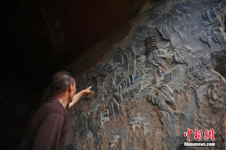 7月15日，甘肅省平?jīng)鍪袥艽h百里石窟長廊羅漢洞石窟內(nèi)，該窟文保員郭建平介紹窟內(nèi)石刻彩繪壁畫。郭建平家中三代人曾自發(fā)保護(hù)羅漢洞石窟。羅漢洞石窟遺存40余個(gè)窟龕，以北魏至清代風(fēng)格為主。中新社記者 李亞龍 攝