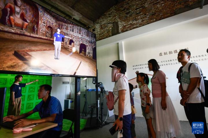 7月22日，游客體驗“尋境敦煌——數(shù)字敦煌沉浸展”后，在虛擬演播廳拍攝一段真人與洞窟虛擬場景交互的視頻。新華社記者 郎兵兵 攝</p>
<p>