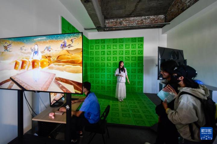 7月22日，游客體驗“尋境敦煌——數(shù)字敦煌沉浸展”后，在虛擬演播廳拍攝一段真人與洞窟虛擬場景交互的視頻。新華社記者 郎兵兵 攝</p>
<p>